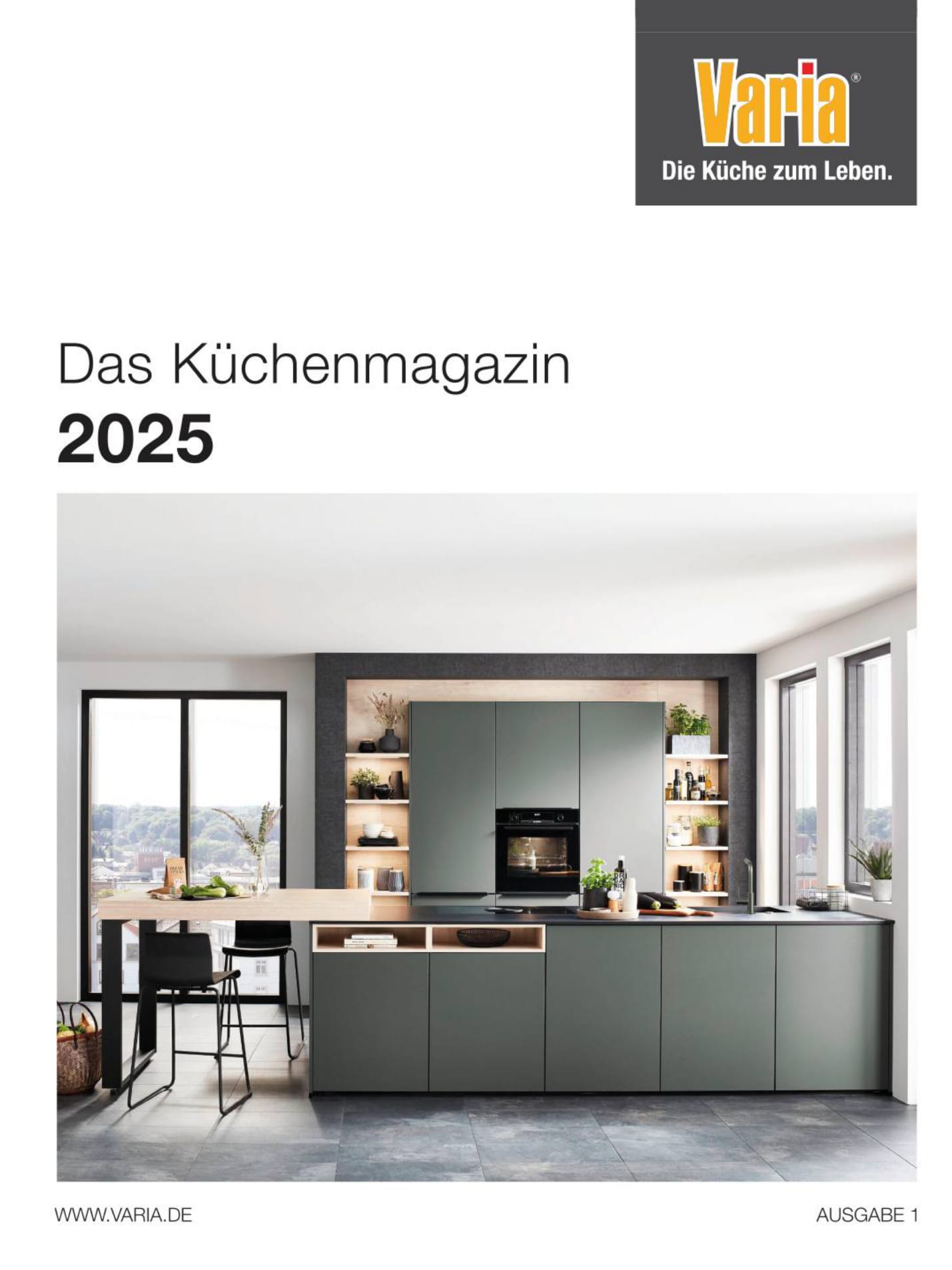 Titelseite des Küchenmagazins 2025 von varia: eine graugrüne Küche mit Holztisch vor großen Fenstern