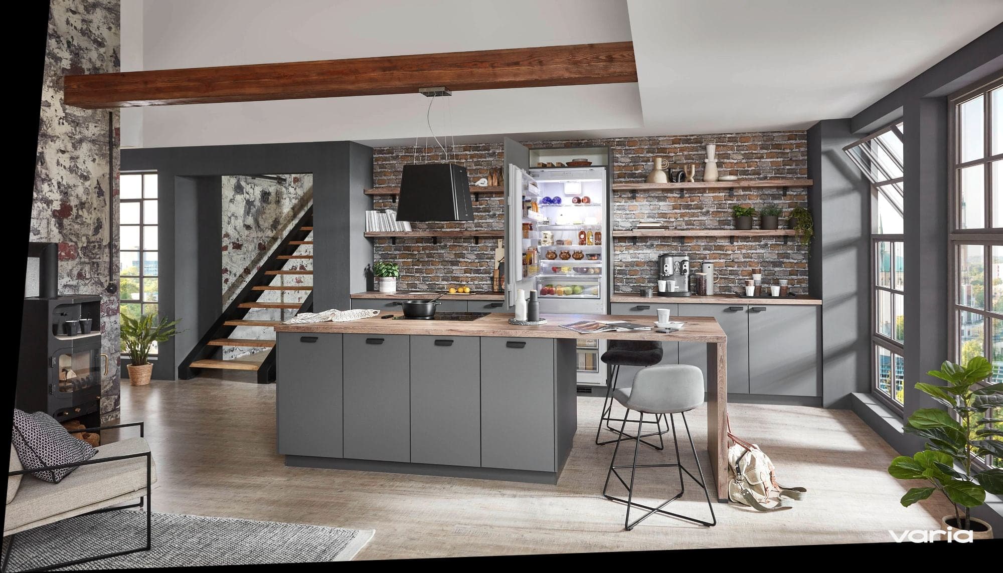 Geöffneter Einbaukühlschrank in einer grauen Küche mit Backsteinwand und Kochinsel