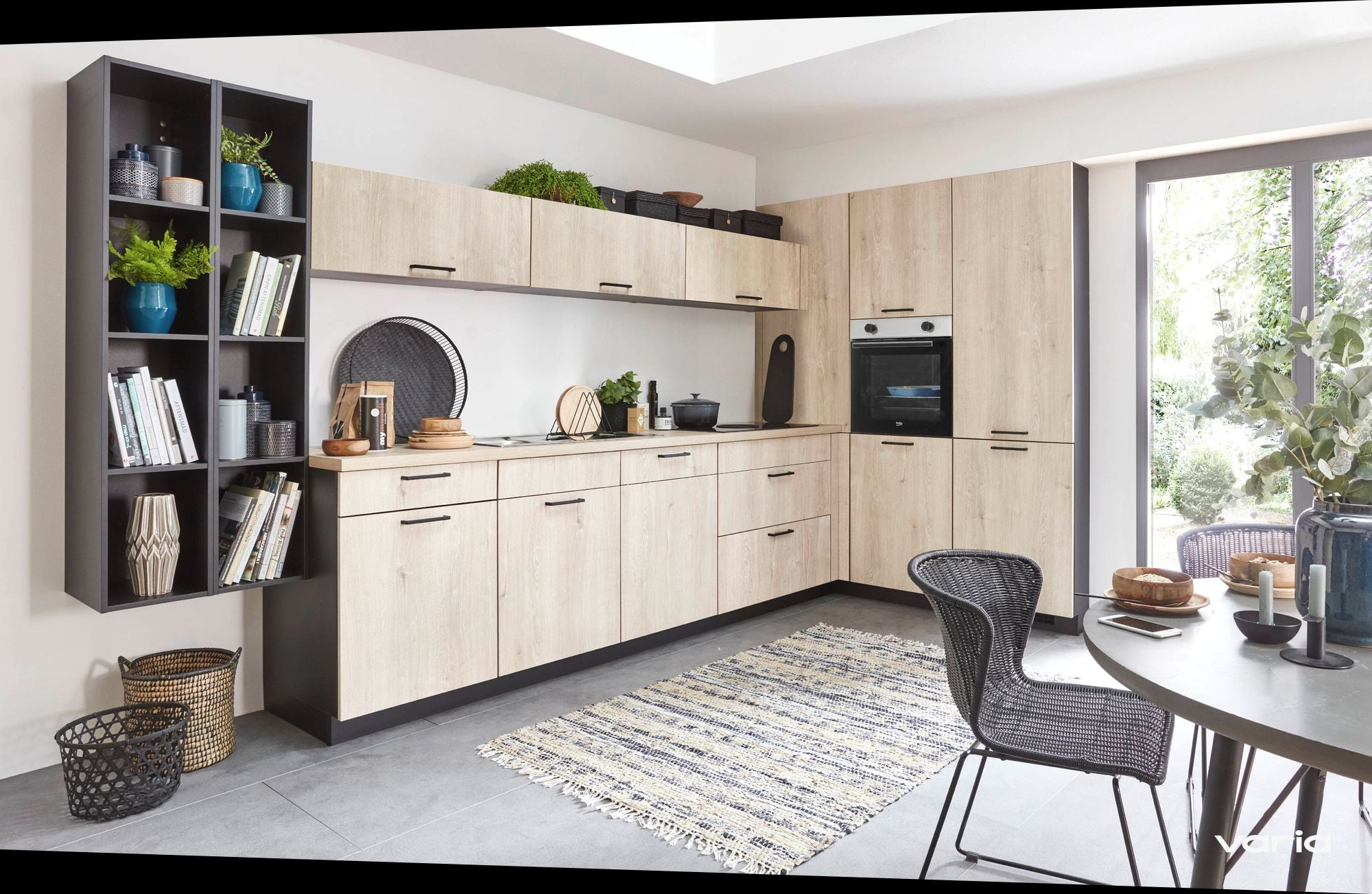 Helle Küche in Holzoptik, rechts eine offene Terrassentür mit Blick in einen begrünten Garten
