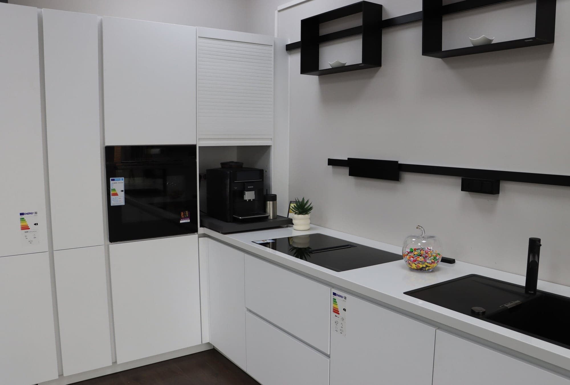 Weiße Küchenzeile mit eingebautem Kaffeevollautomaten, Backofen und Induktionskochfeld