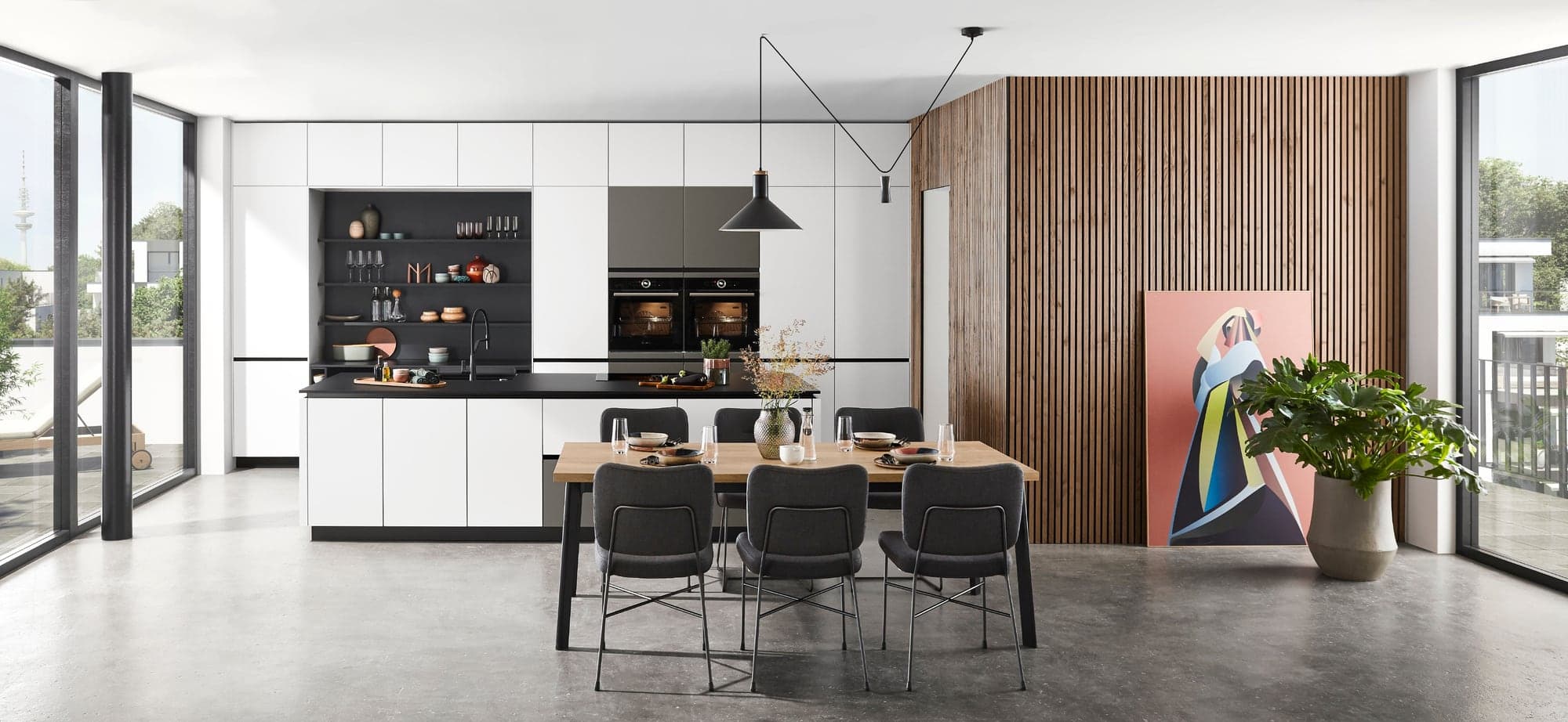 Helle moderne Küche mit flächenbündiger Zeile, Holzwand und langem Esstisch
